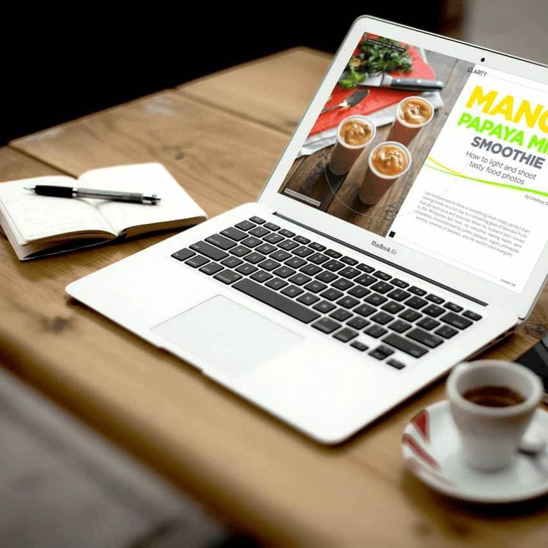 A laptop on a table with a cup of coffee.