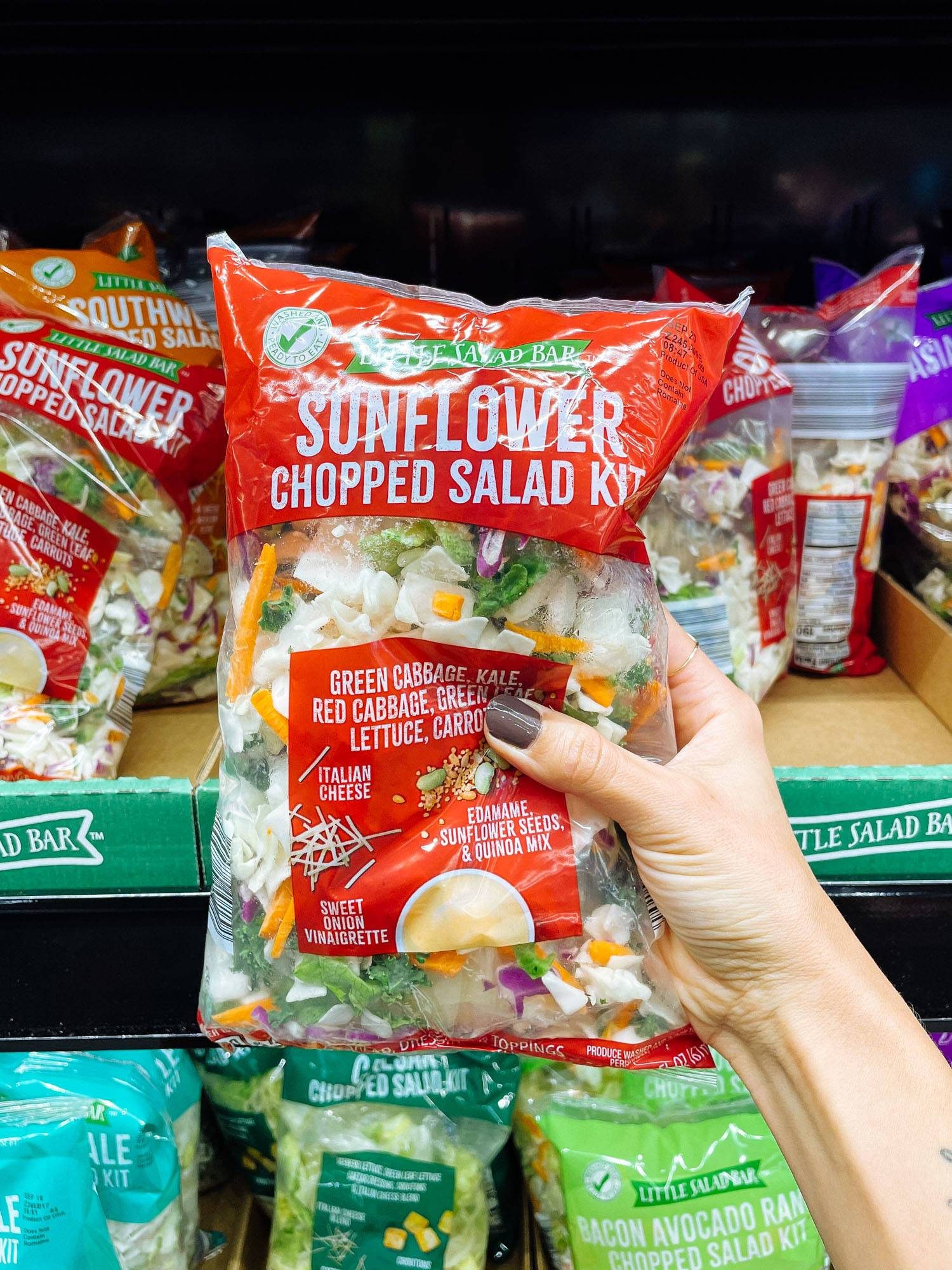 White hand holding a sunflower chopped salad kit from ALDI.