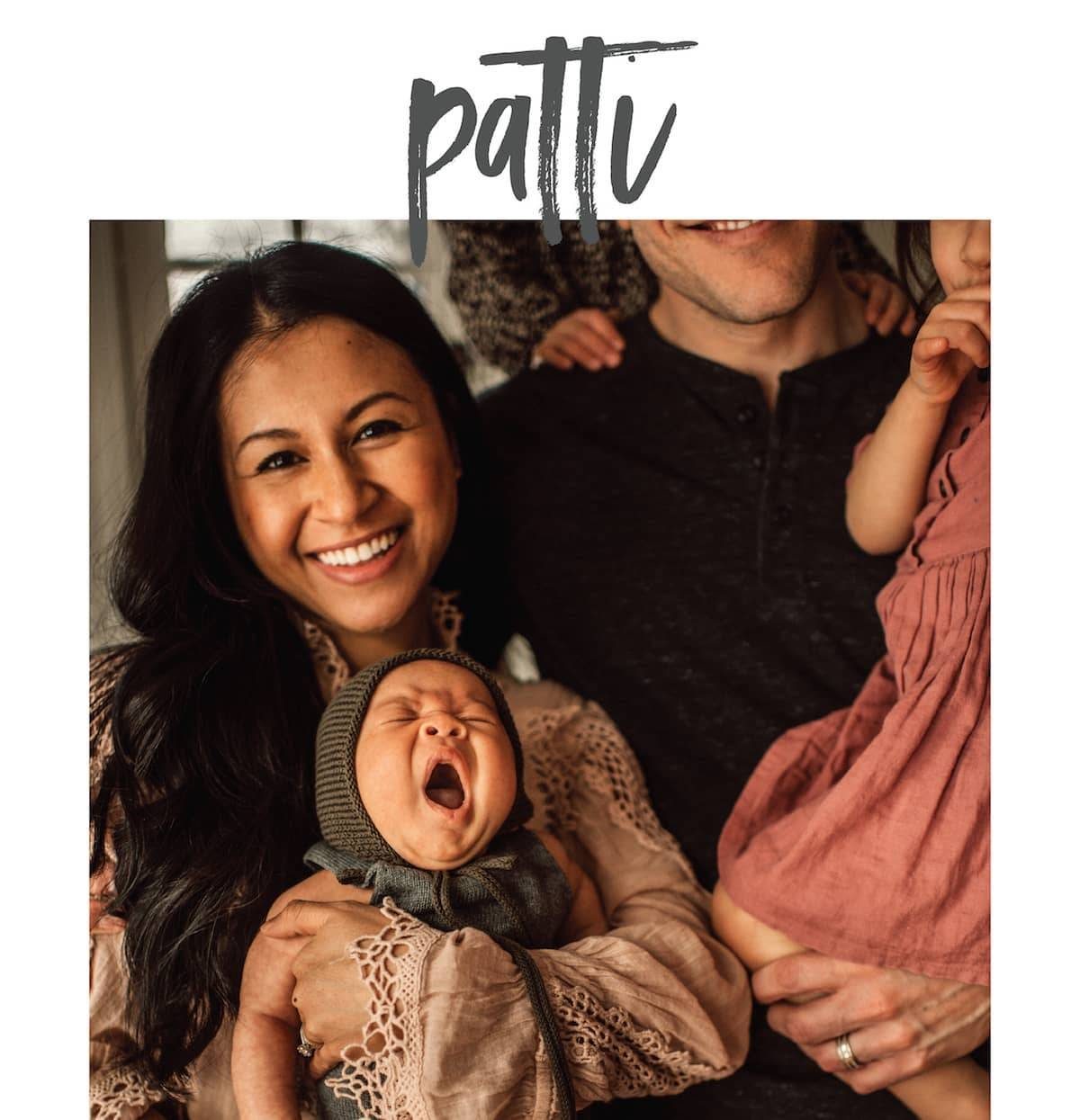 A smiling couple holding a girl and and infant who is yawing.