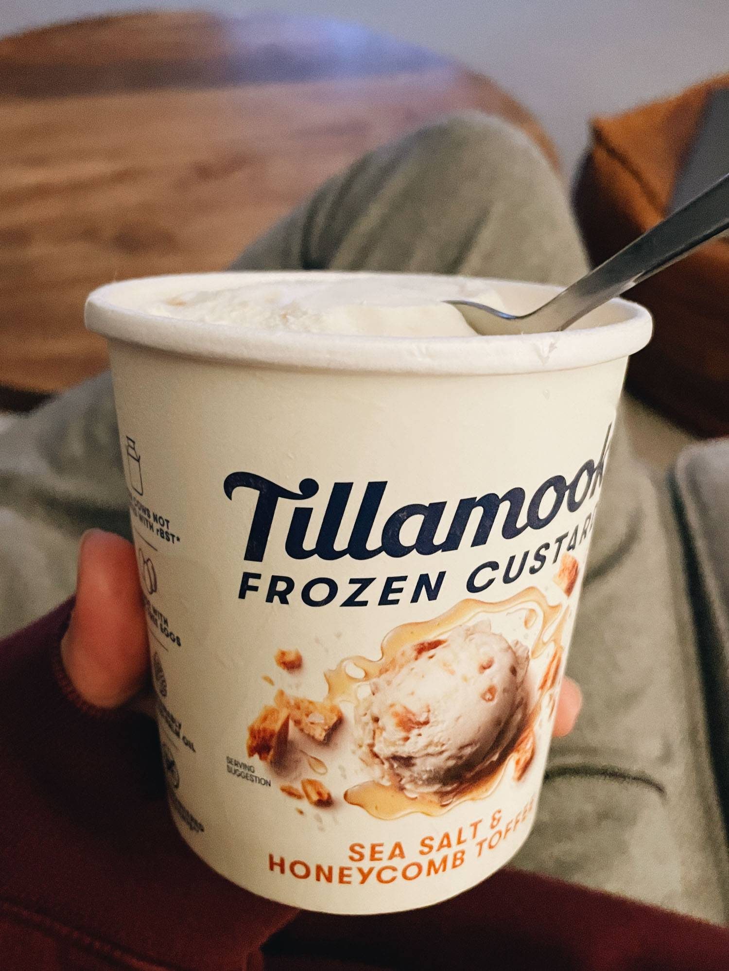 Woman holding ice cream tub with spoon in it.